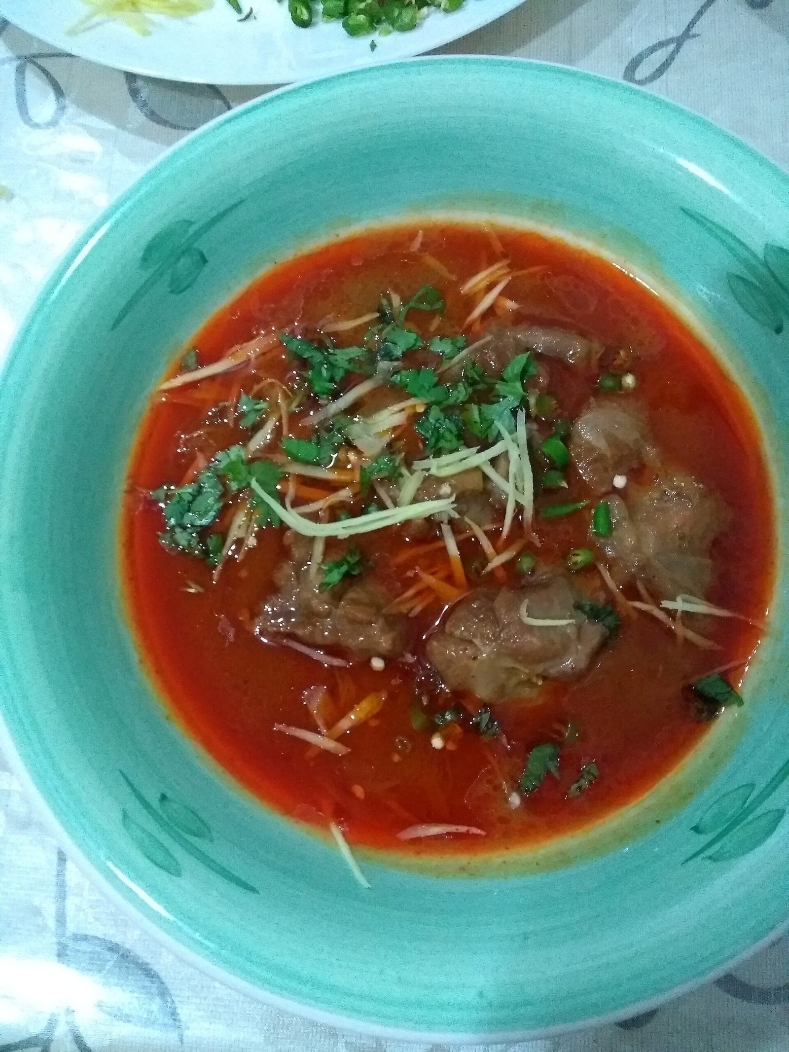 Beef nihari garnished with ginger and coriander