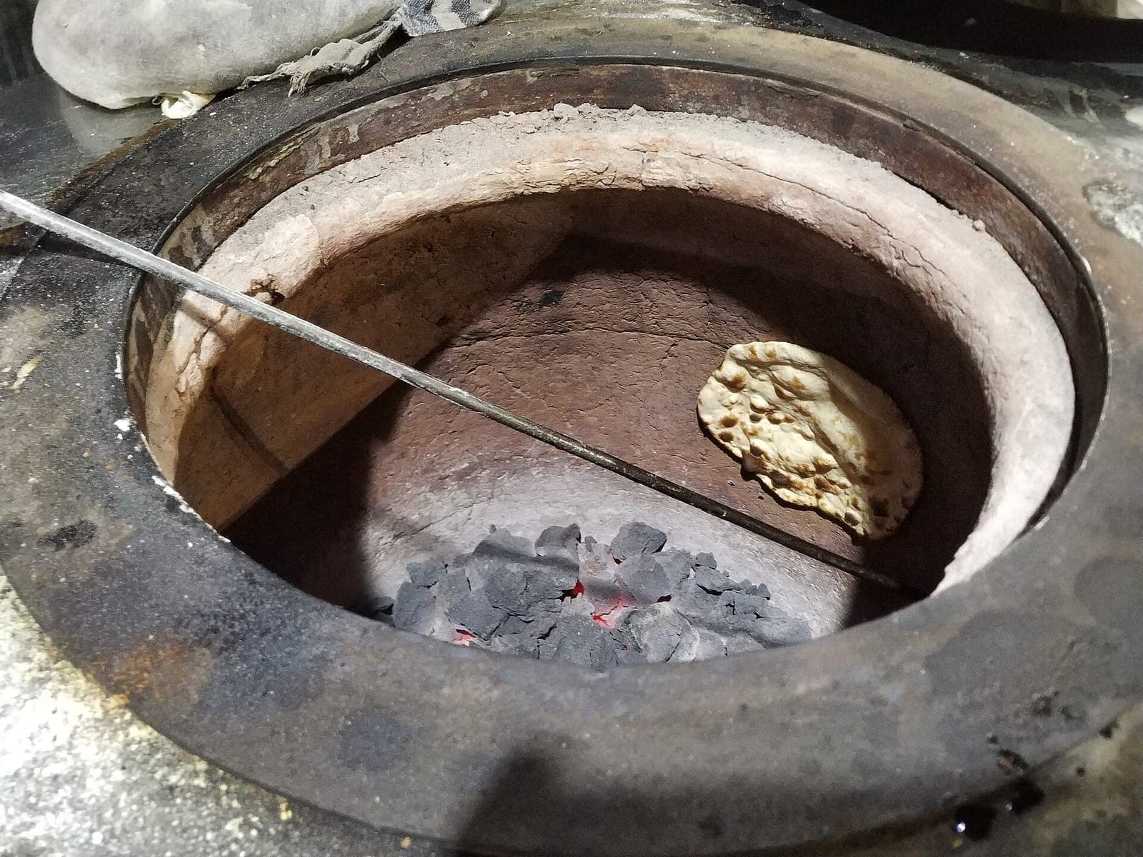 Fresh naan baking inside a clay tandoor