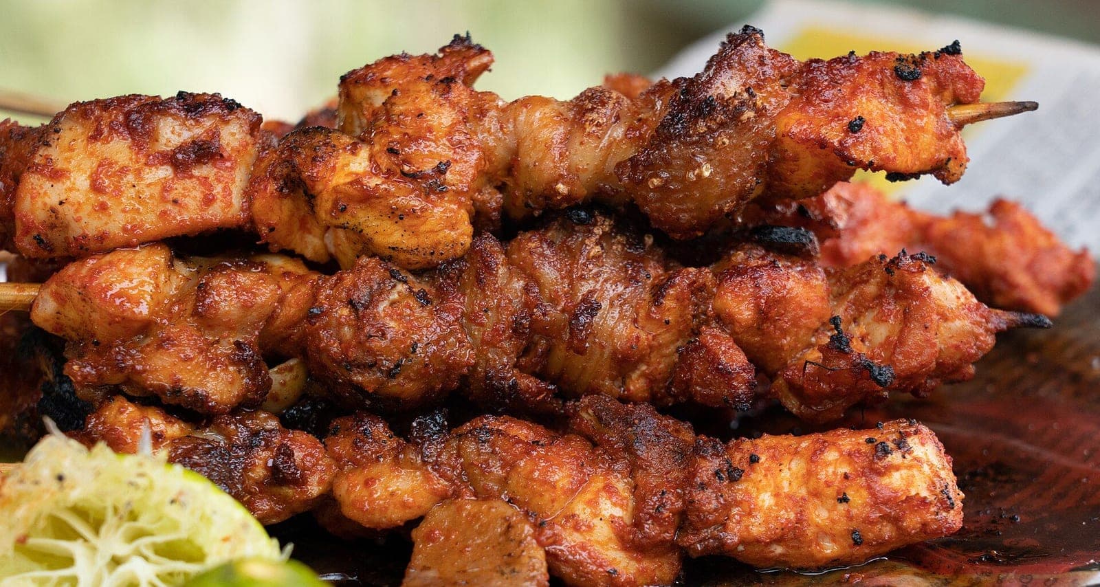 Chicken tikka skewers grilled over coals