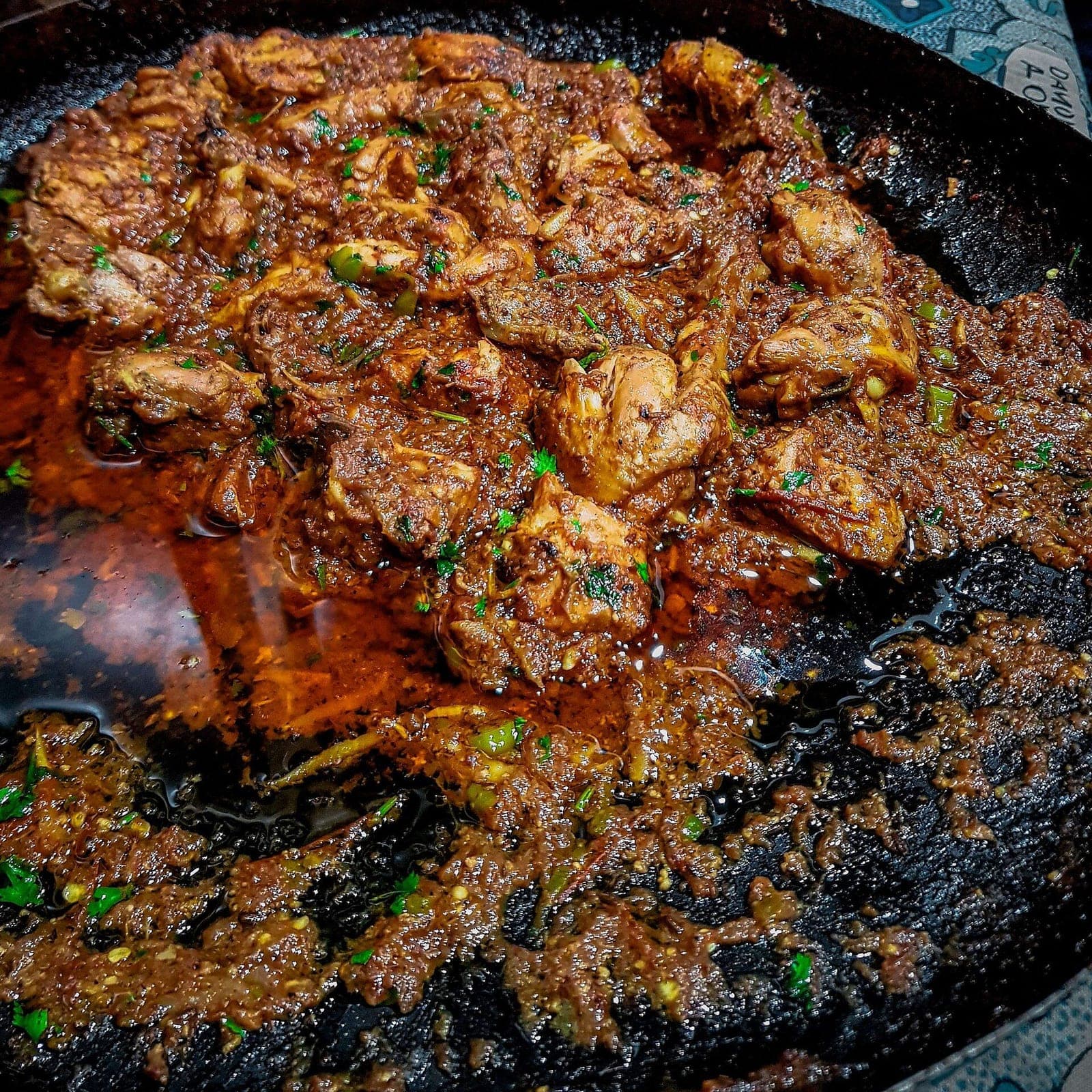 Chicken karahi in a traditional iron wok
