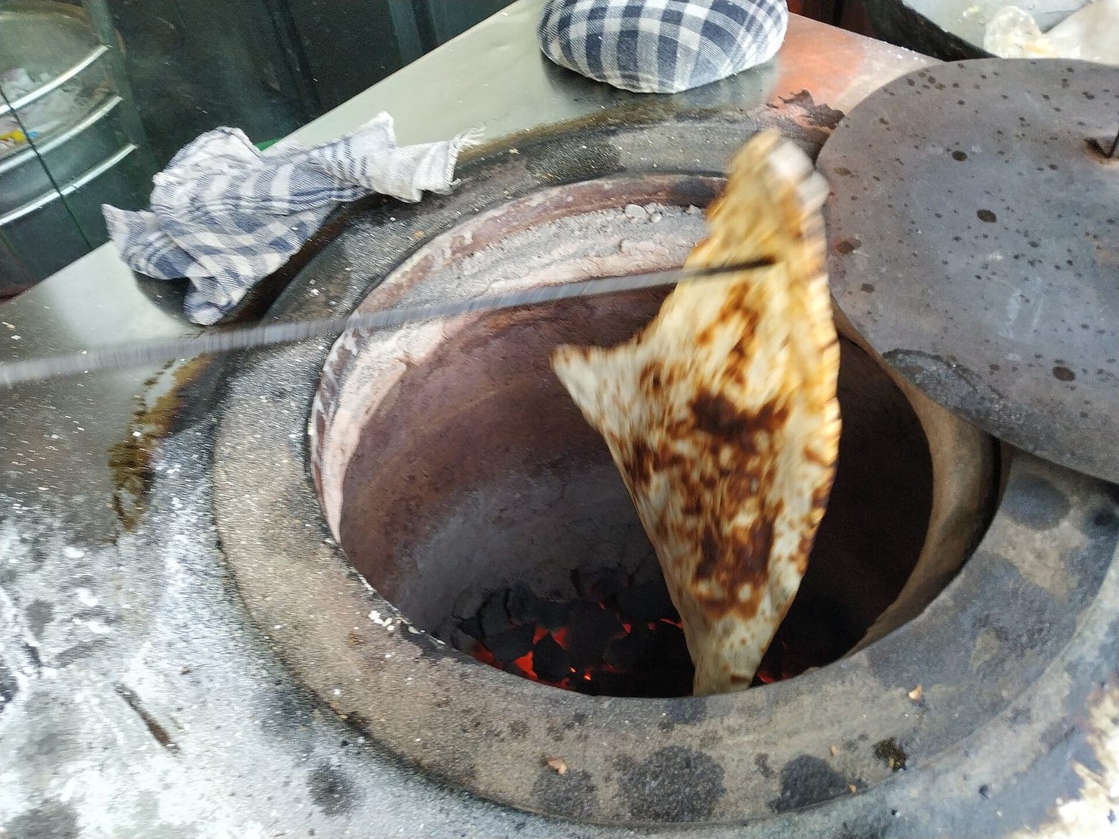 Naan baking inside a clay tandoor